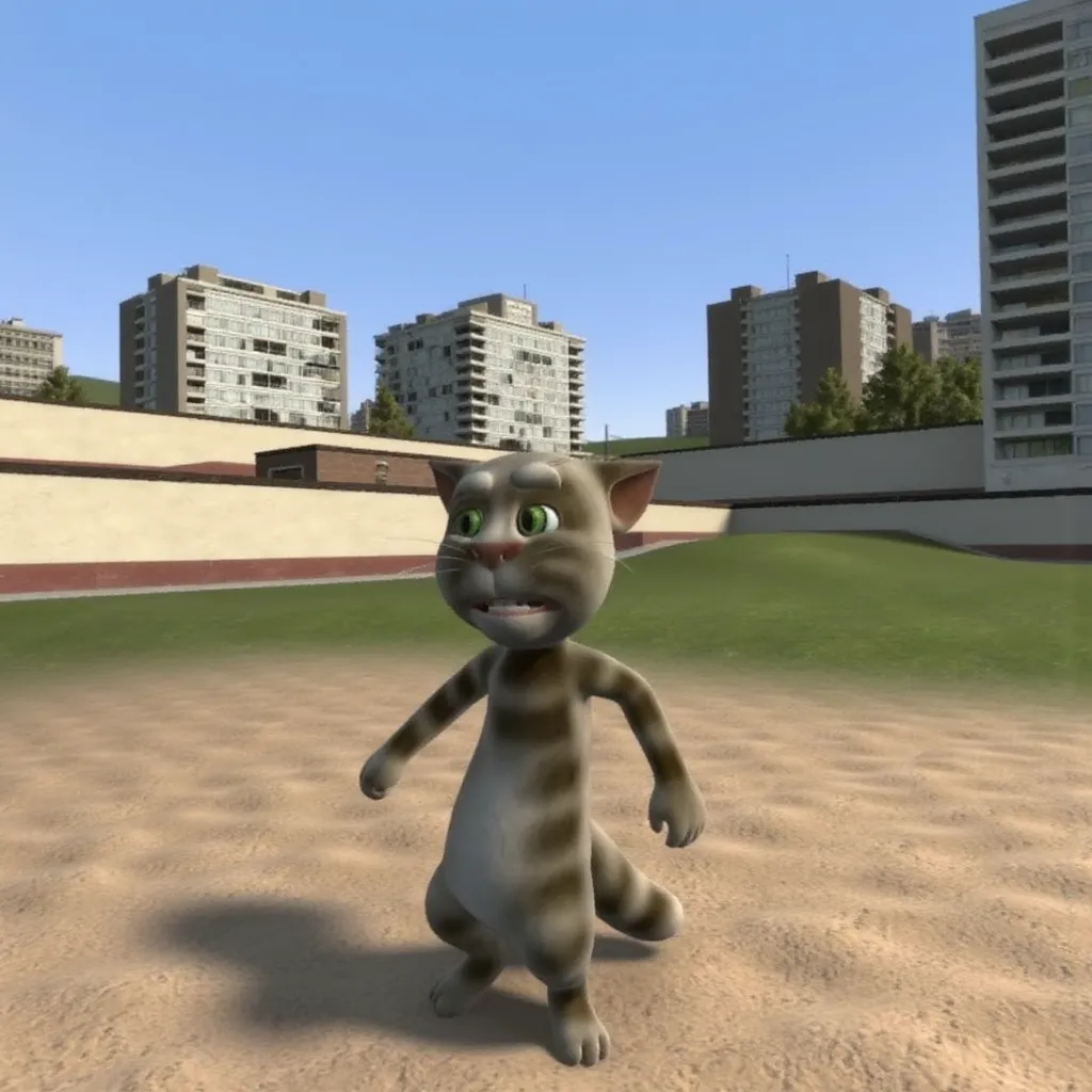 Cat cartoon 3d model lanky with gray fur and green eyes in gm_construct, a scene from the video game "Garry's Mod" featuring a virtual urban landscape. The image shows an open area with a mix of grass and sand in the foreground, bordered by modern buildings in the background. The sky is clear and blue, and the environment appears to be part of a digital sandbox setting.