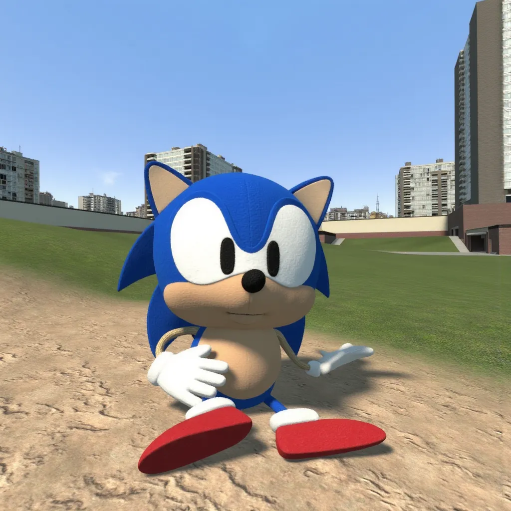 gm_construct, a scene from the video game "Garry's Mod" featuring a virtual urban landscape. The image shows an open area with a mix of grass and sand in the foreground, bordered by modern buildings in the background. The sky is clear and blue, and the environment appears to be part of a digital sandbox setting. Stringy Sonic Plush, the character is blue with large eyes, white gloves, and red shoes with white cuffs. It's sitting.